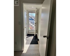 A hallway with a black mat on the floor leading to a door.