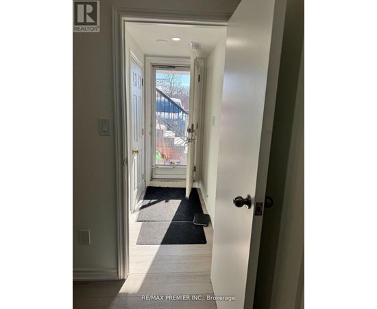 A hallway with a black mat on the floor leading to a door.