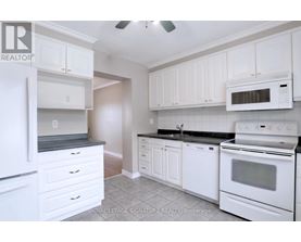 A white kitchen with a refrigerator, microwave, oven, and cabinets.