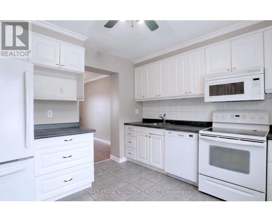 A white kitchen with a refrigerator, microwave, oven, and cabinets.