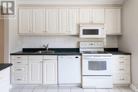 A white kitchen with a black counter top and white appliances.
