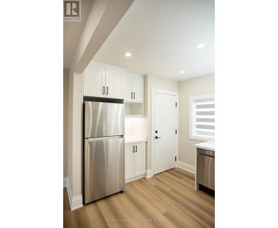 A kitchen with a stainless steel refrigerator and wooden floors.