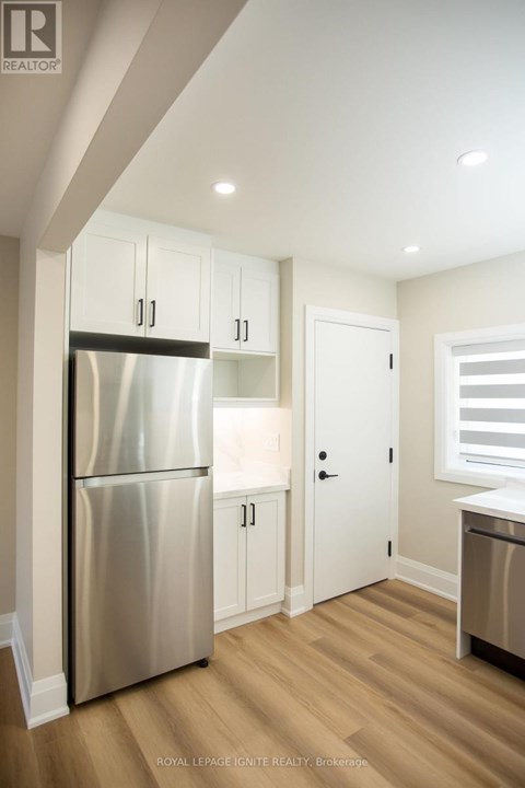 A kitchen with a stainless steel refrigerator and wooden floors.