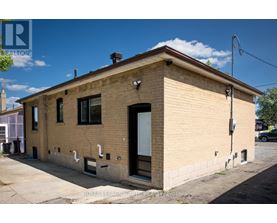 A small, beige building with a black door and windows.