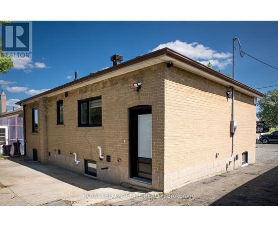 A small, beige building with a black door and windows.