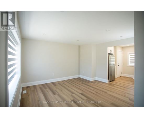 A room with wooden floors and white walls, with a door on the right side.