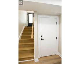 A white door with a black handle is in a room with a staircase.