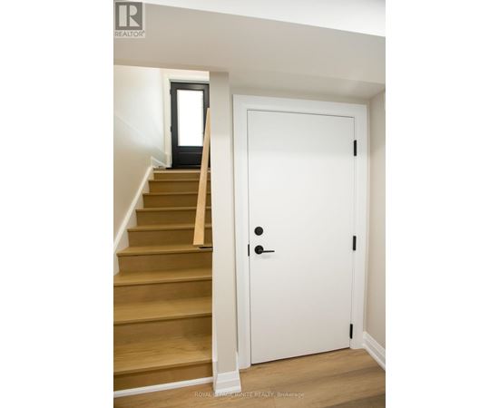 A white door with a black handle is in a room with a staircase.