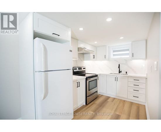 A white refrigerator is in a kitchen with white cabinets and stainless steel appliances.