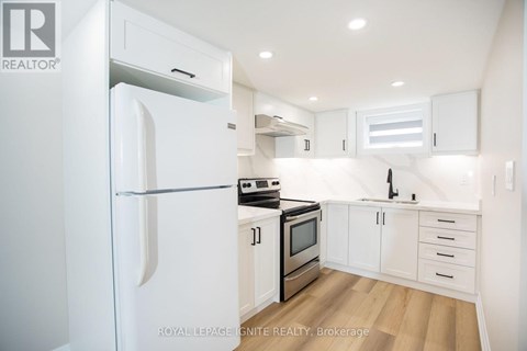 A white refrigerator is in a kitchen with white cabinets and stainless steel appliances.