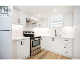 A white kitchen with a stove, oven, and sink.
