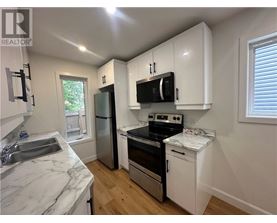A kitchen with white cabinets and a marble countertop.
