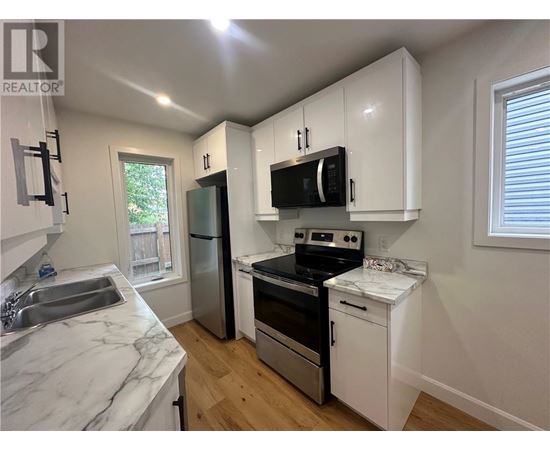 A kitchen with white cabinets and a marble countertop.