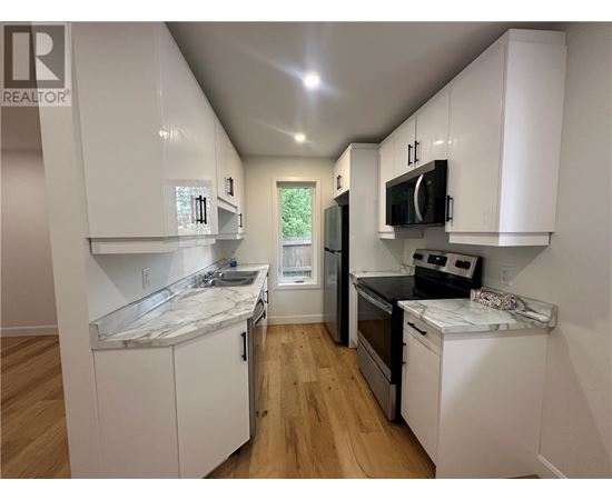 A kitchen with white cabinets and a marble countertop.