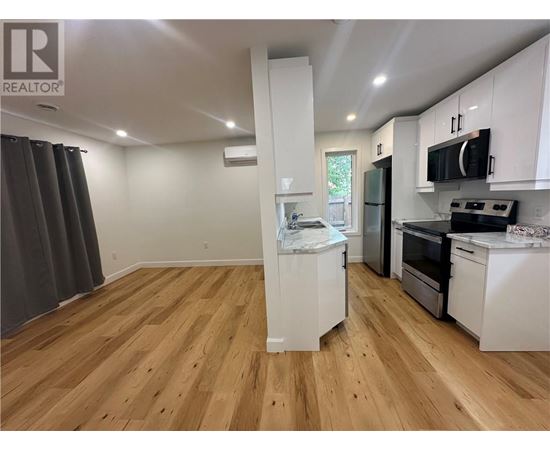 A kitchen with white cabinets and wooden floors.
