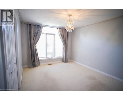 A bedroom with a large window and a chandelier.