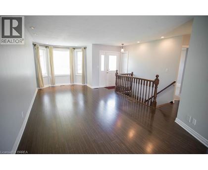 A spacious room with wooden floors and a staircase.