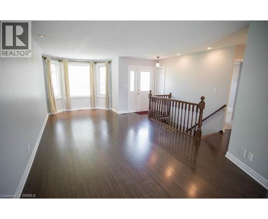 A spacious room with wooden floors and a staircase.