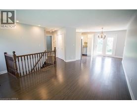 A large empty room with wood flooring and a chandelier.