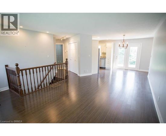 A large empty room with wood flooring and a chandelier.