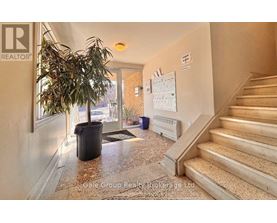 A hallway with a plant, a calendar, and a staircase.