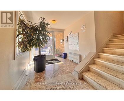 A hallway with a plant, a calendar, and a staircase.