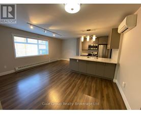 A spacious kitchen and living room with hardwood floors and a large window.