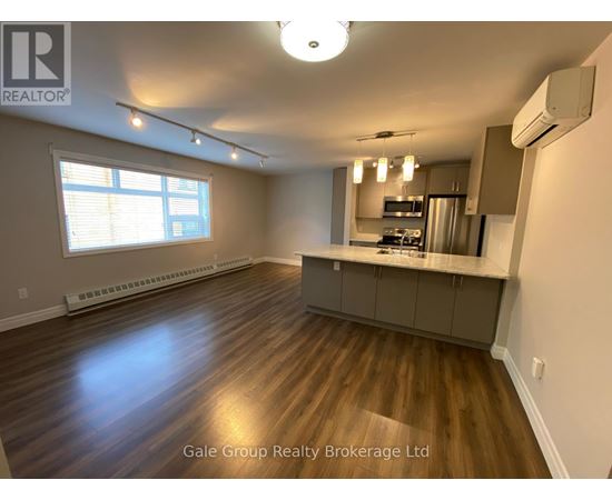 A spacious kitchen and living room with hardwood floors and a large window.