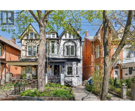 A Victorian style house with a front porch and a tree in front.