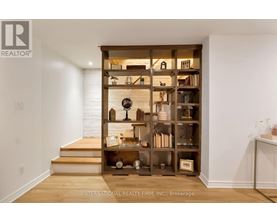 A wooden bookshelf filled with various items sits in the corner of a room.