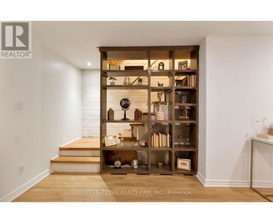 A wooden bookshelf filled with various items sits in the corner of a room.