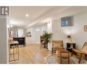 A well-lit, spacious living room with a dining area in the background.