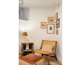 A living room with a chair, ottoman, and pictures on the wall.
