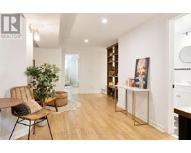 A room with a wooden floor and white walls, furnished with a chair, a table, and a potted plant.