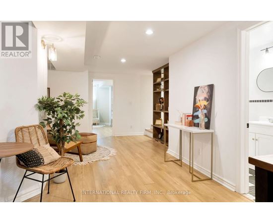 A room with a wooden floor and white walls, furnished with a chair, a table, and a potted plant.