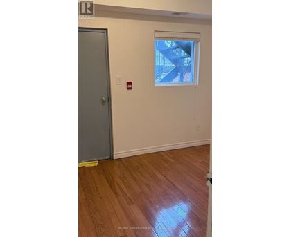 A room with a wooden floor and a window showing a staircase outside.
