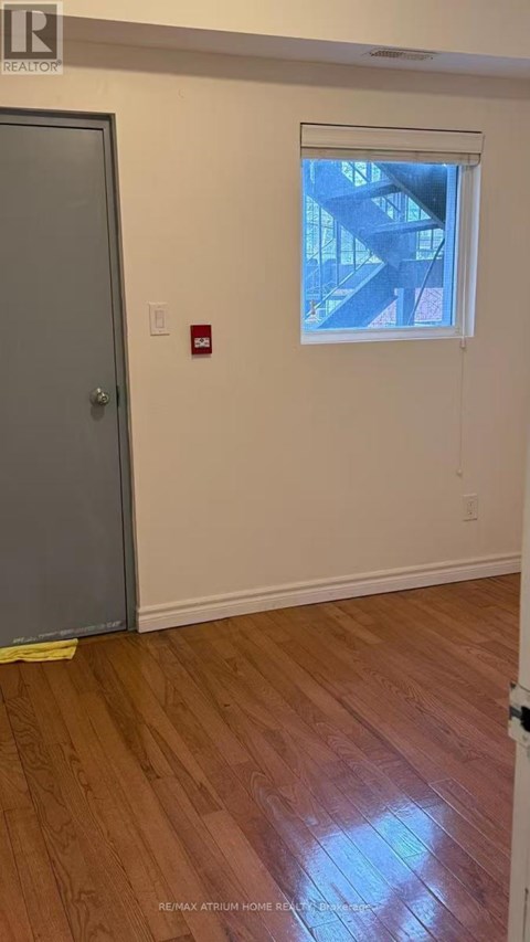 A room with a wooden floor and a window showing a staircase outside.