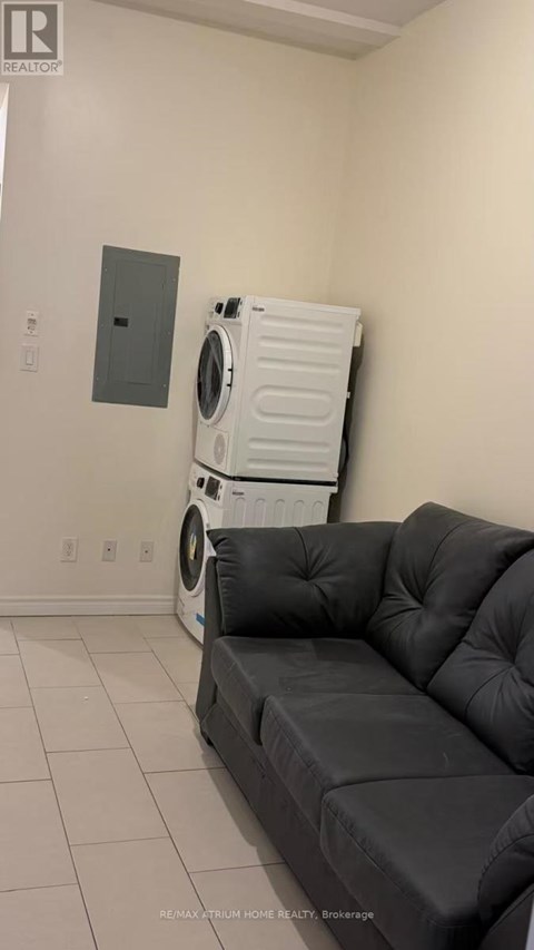 A black sofa in a room with a washing machine behind it.