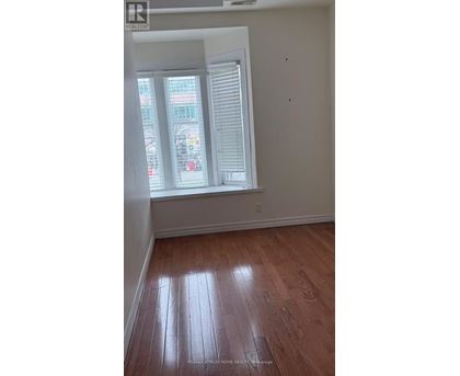 A room with wooden flooring and a window with blinds.