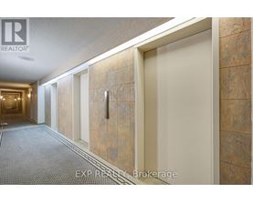 A hallway with a carpeted floor and tiled walls.
