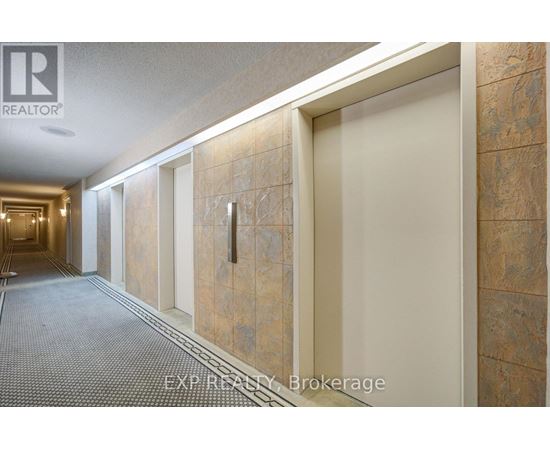 A hallway with a carpeted floor and tiled walls.
