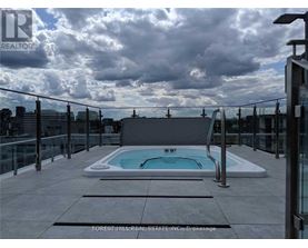 A rooftop pool with a glass railing and a cloudy sky.
