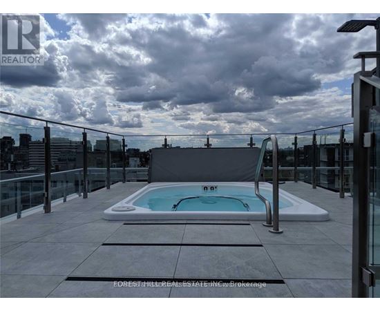 A rooftop pool with a glass railing and a cloudy sky.