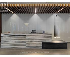 A modern office lobby with a wooden ceiling and a stone reception desk.