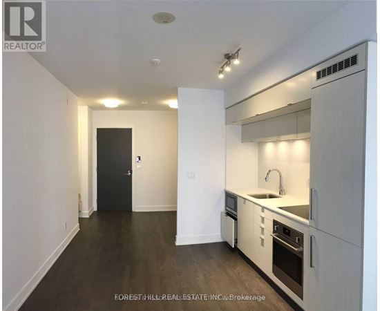 A modern kitchen with white cabinets and a black door.