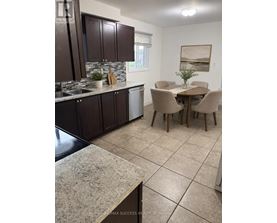 A kitchen with brown cabinets and a dining table.