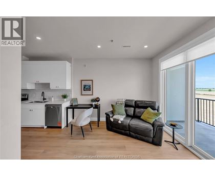 A modern living room with a grey sofa and a dining table with chairs.