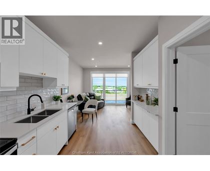 A modern kitchen with white cabinets and a large window.