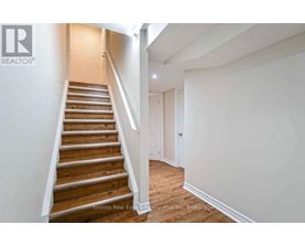 A staircase in a house with a brokerage logo on the wall.