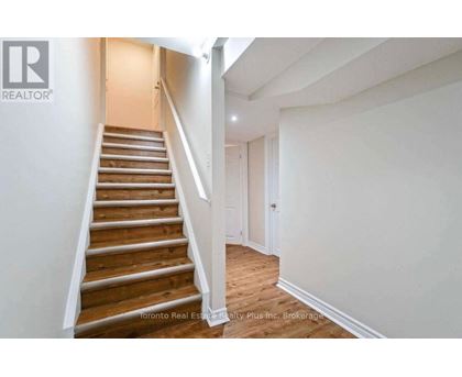 A staircase in a house with a brokerage logo on the wall.